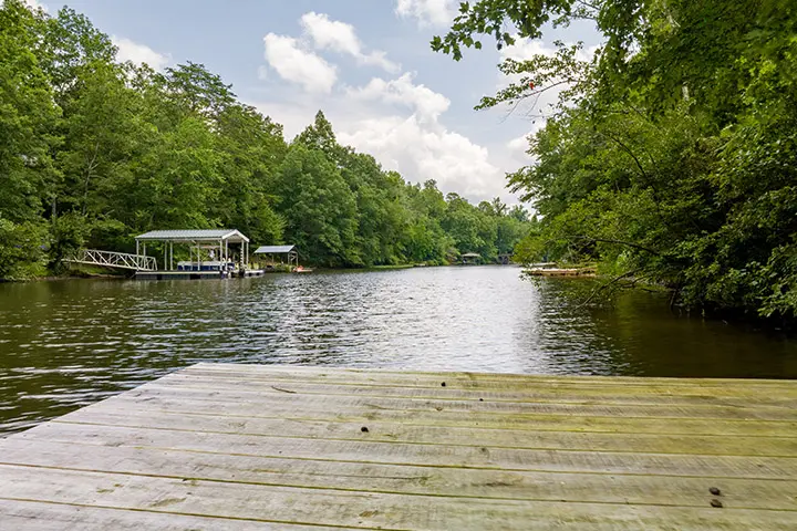 A wooden dock with a boat in the middle of a wooded area.