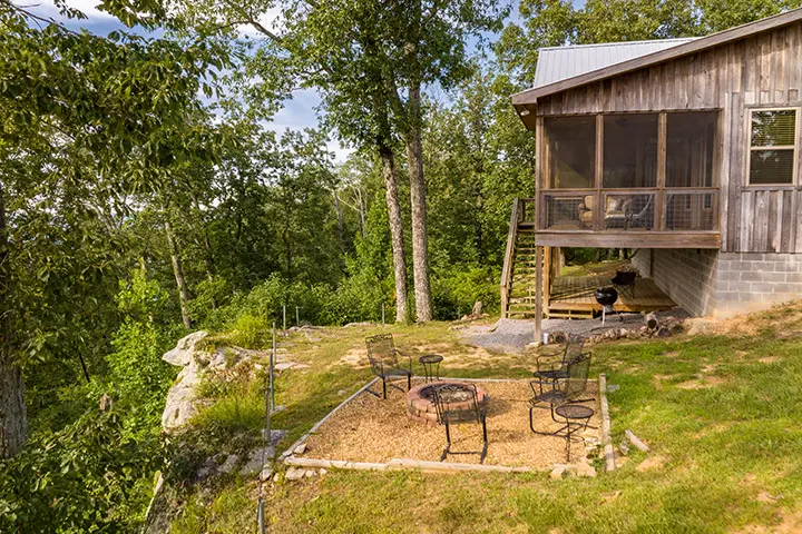 A cabin with a fire pit on the side of a hill.