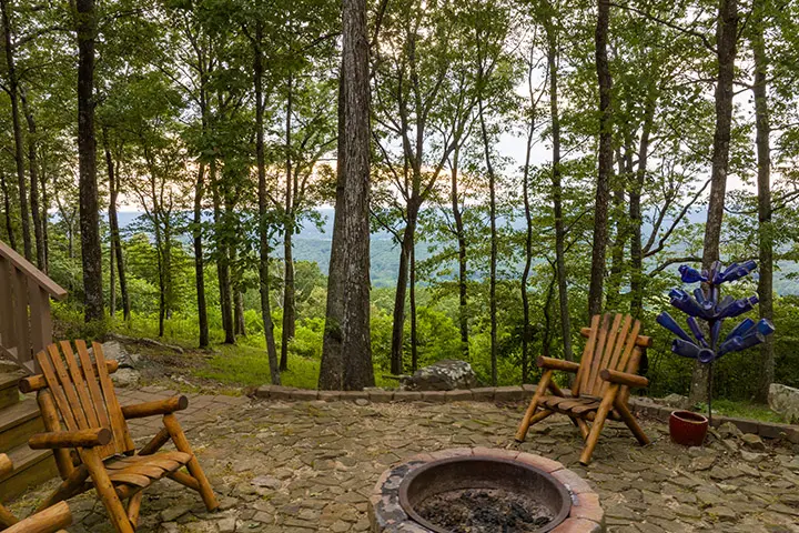 A fire pit sits in the middle of a wooded area.