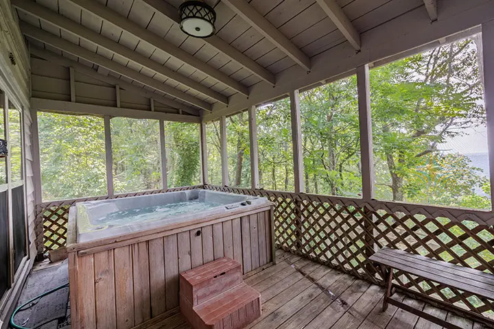 A hot tub on a deck overlooking a wooded area.