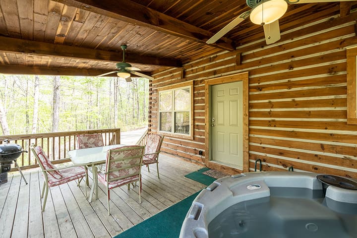 A hot tub on the deck of a log cabin.