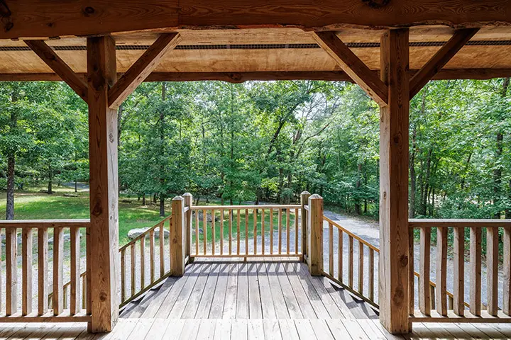 A wooden porch overlooking a wooded area.