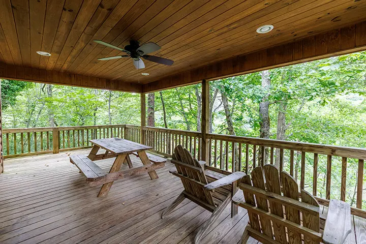 A deck with two wooden chairs and a picnic table.