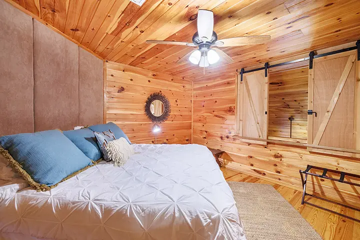 A bedroom in a log cabin with a bed and a ceiling fan.