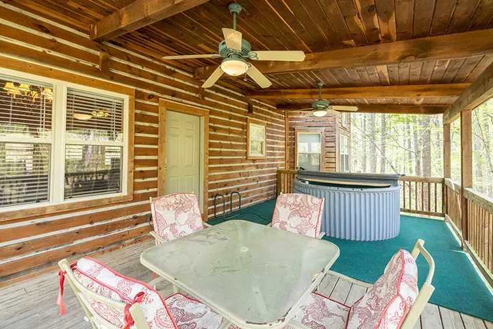 A cabin with a hot tub on the porch.