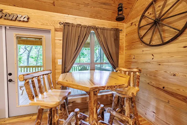 A dining table and chairs in a log cabin.