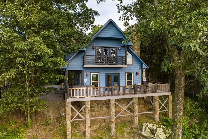 An aerial view of a blue cabin in the woods.