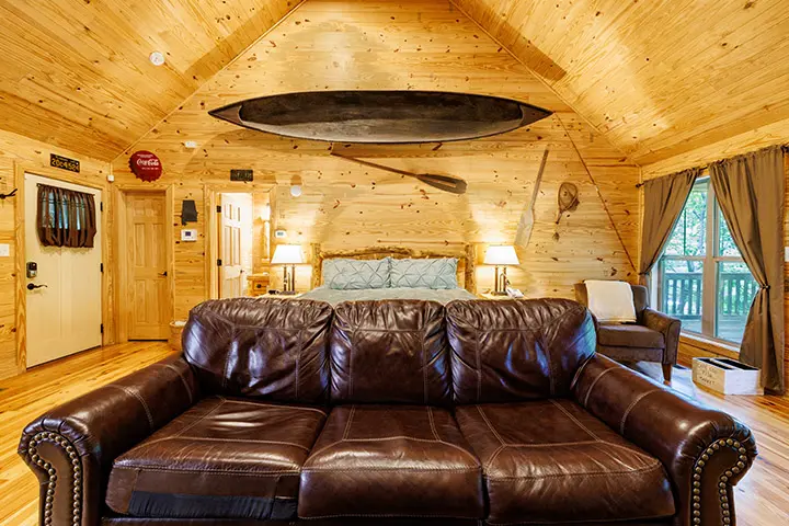 A cabin with a leather couch and a bed.