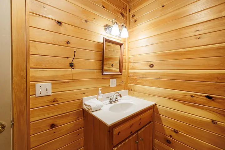 A bathroom with wood paneling and a sink.