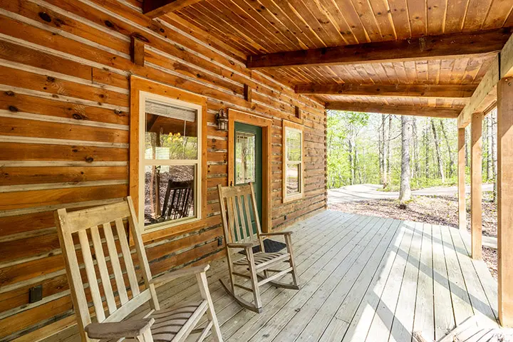 Rocking chairs on the porch of a log cabin.