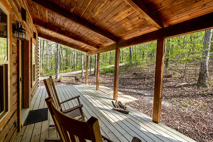 The porch of a log cabin with rocking chairs.