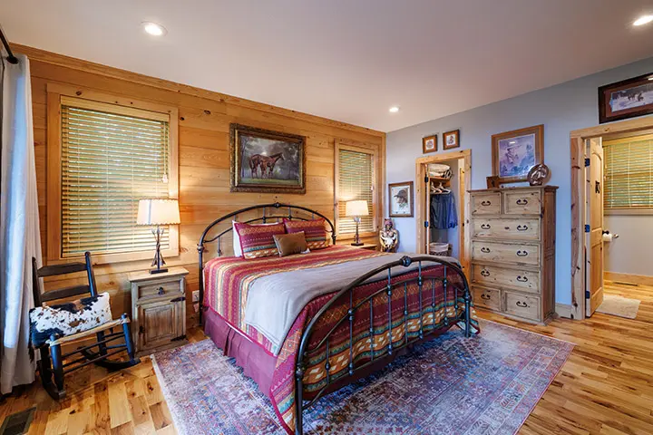 A bedroom with a bed and dresser in a log cabin.