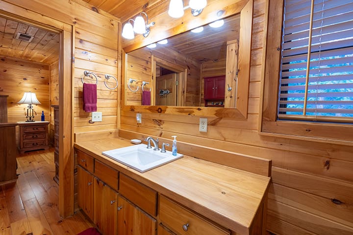 A bathroom with a sink and mirror in a log cabin.
