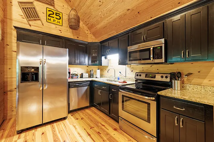 A kitchen in a log cabin with stainless steel appliances.