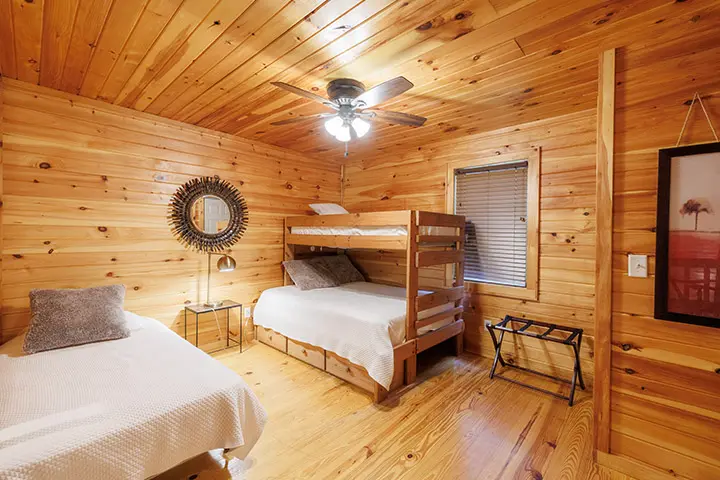 A cabin bedroom with two bunk beds and a ceiling fan.