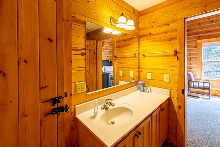 A bathroom in a log cabin with a sink and mirror.
