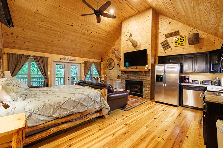 A bedroom in a log cabin with a fireplace and tv.