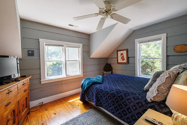 A bedroom with wood floors and a ceiling fan.