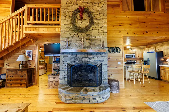 A log cabin with a fireplace and stairs.