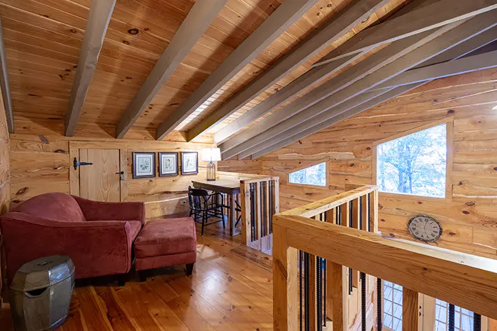 A living room in a log cabin with wood floors.