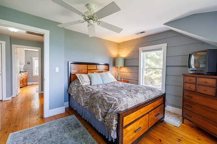 A bedroom with hardwood floors and a ceiling fan.