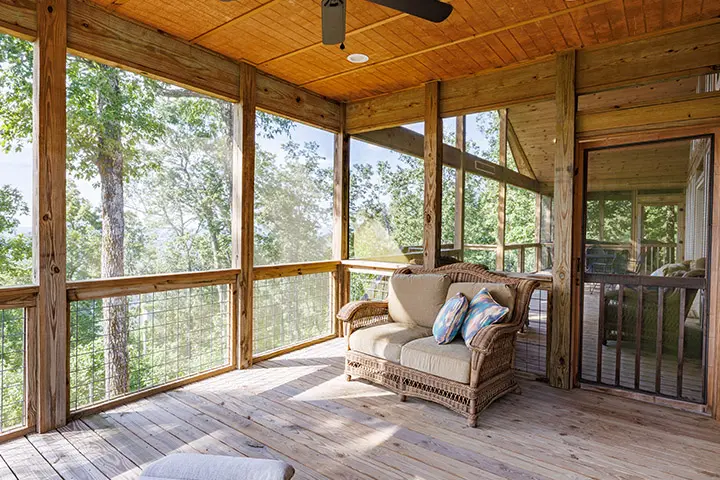 A screened in porch overlooking a wooded area.