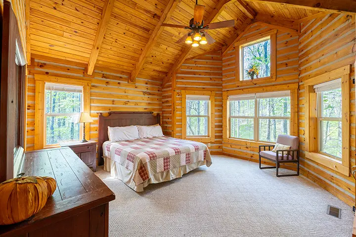 A bedroom in a log cabin with a bed and a window.