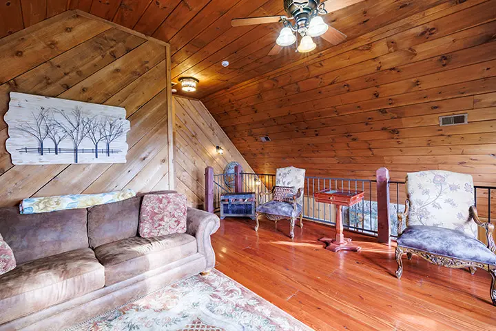 A living room with wood paneling and a ceiling fan.