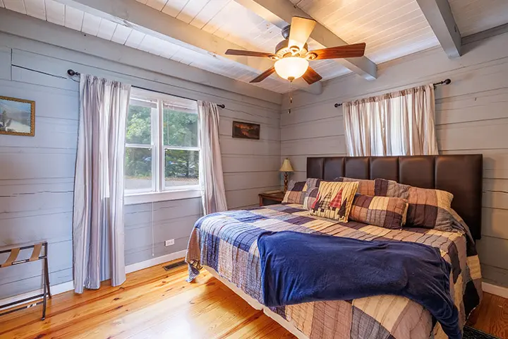 A bedroom with wood floors and a ceiling fan.