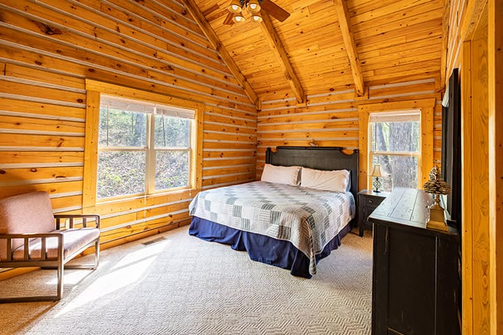 A bedroom in a log cabin with a bed and a bedside table.