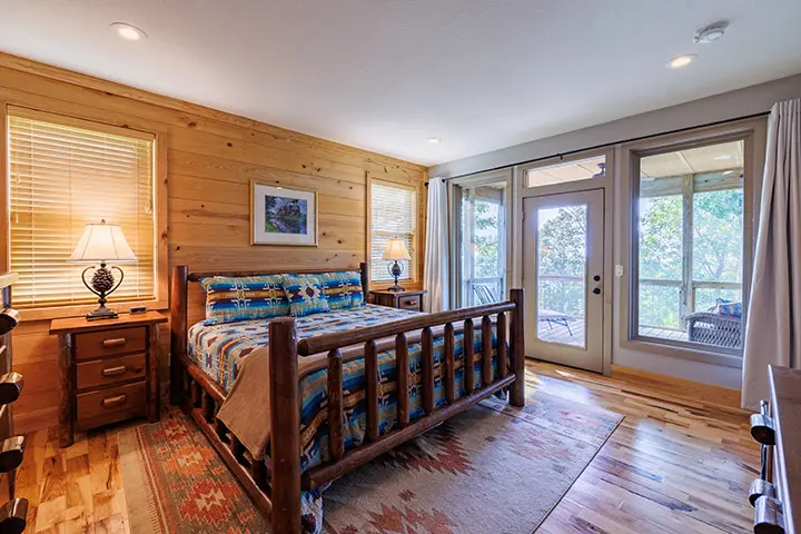 A bedroom in a log cabin with wood floors and a bed.