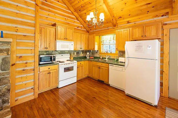 A kitchen in a log cabin with a stove and refrigerator.