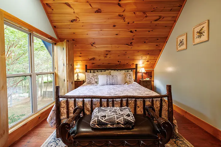 A bedroom in a log cabin with a bed and a chair.