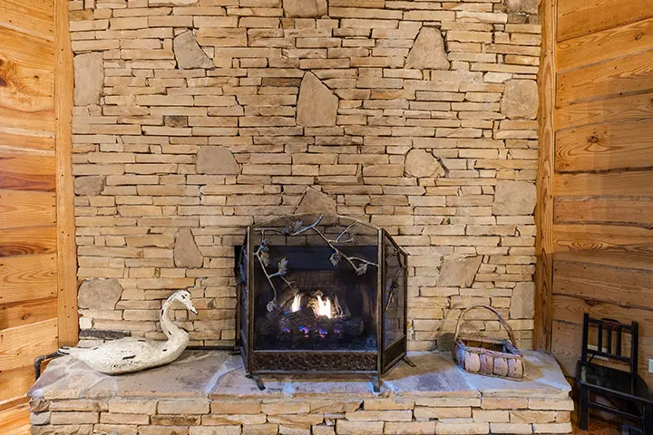 A stone fireplace in a log cabin.