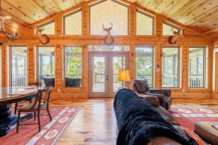 The living room of a log cabin is decorated with deer antlers.