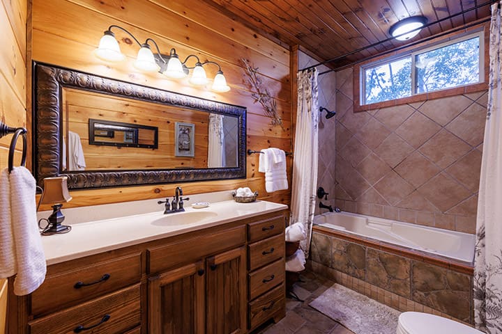 A bathroom in a log cabin with a tub and sink.