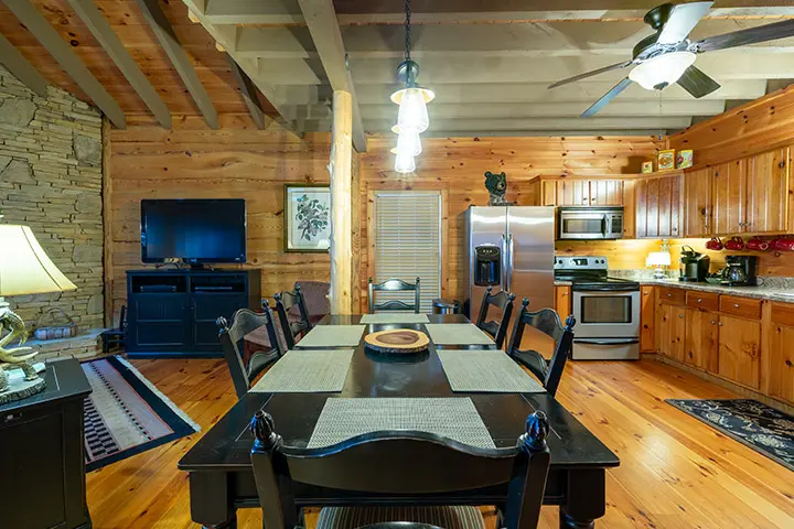 A dining room and kitchen in a log cabin.