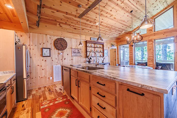 A kitchen in a log cabin with wood paneling.