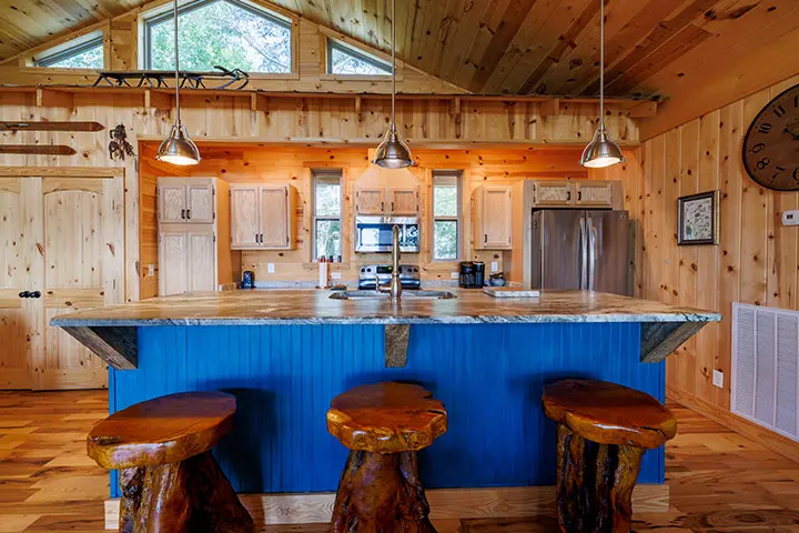 A kitchen with a blue island and stools.