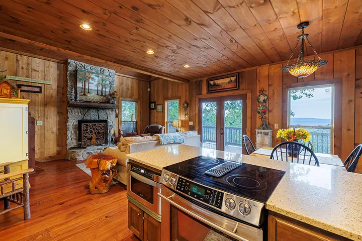 A kitchen in a cabin with wood paneling and a fireplace.