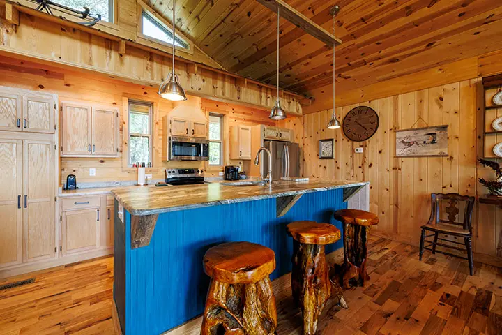 A kitchen in a log cabin with blue stools.