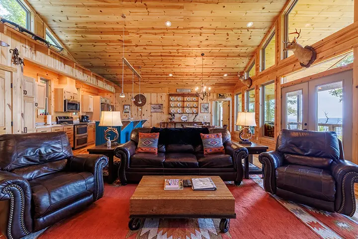 A living room in a log cabin with large windows.