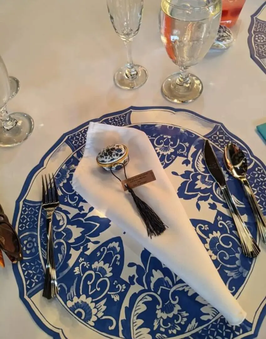 A blue and white place setting with silverware and a tassel.