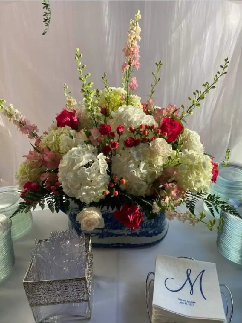 An arrangement of flowers in a blue vase on a table.