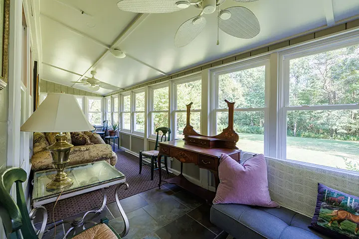 A screened in porch with a fan and a couch.