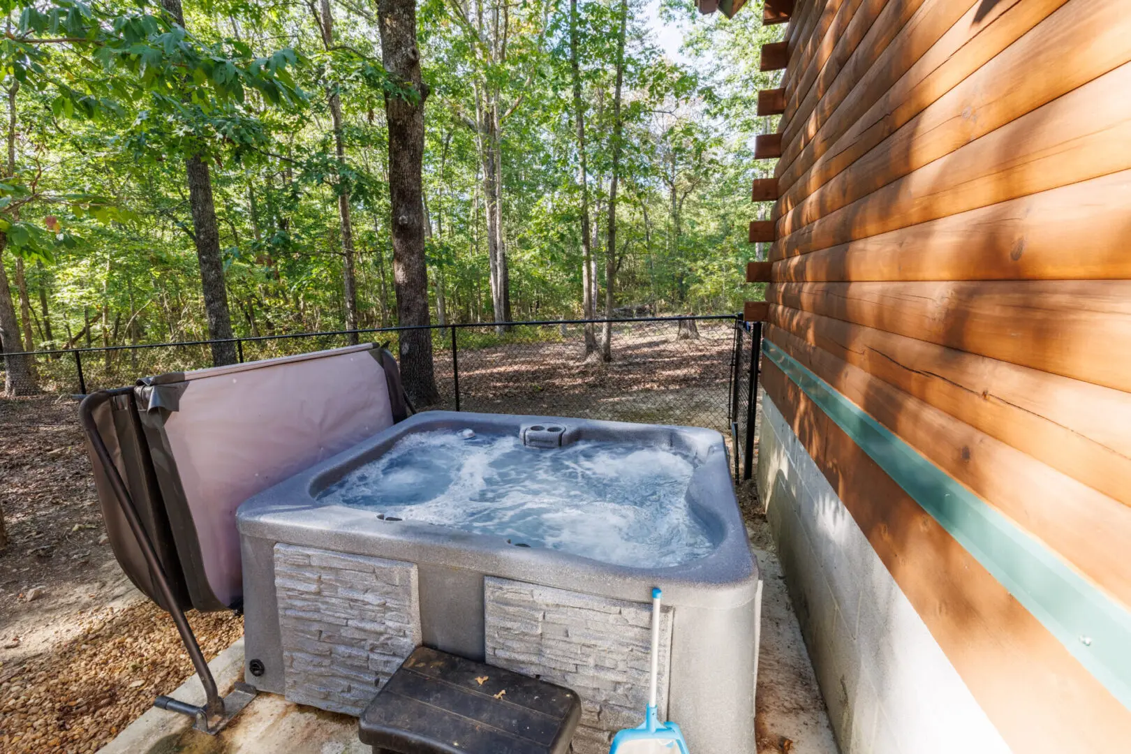 A hot tub in the woods next to a cabin.