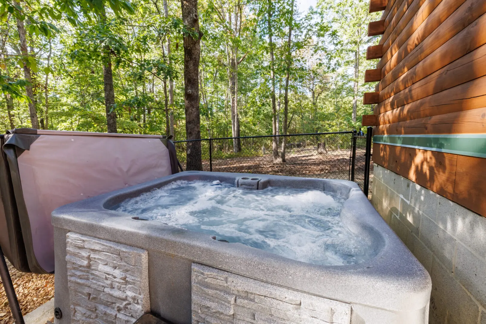 A hot tub in front of a cabin in the woods.