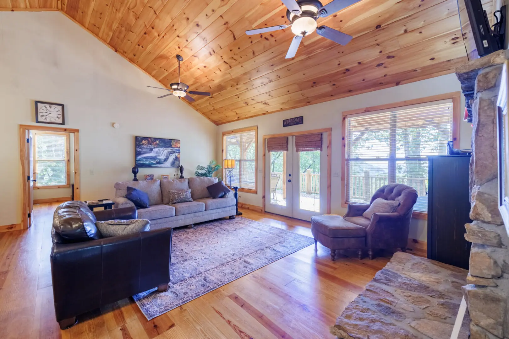 A living room with wood ceilings and a fan.