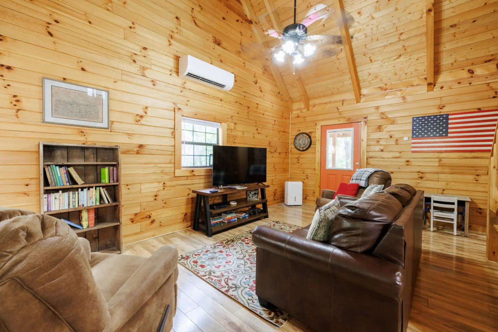 A living room in a log cabin with a tv.