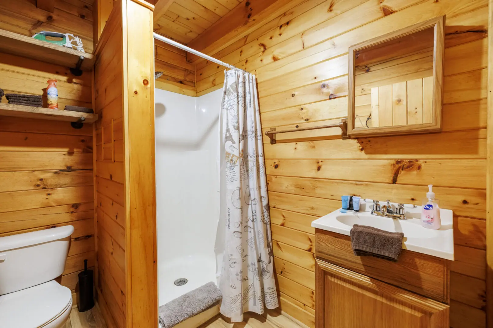 A bathroom with a shower and toilet in a log cabin.